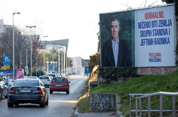 Une voiture passe devant une affiche électorale du président croate sortant et candidat à la présidentielle du Parti social-démocrate (SDP), Zoran Milanovic, dans le centre de Zagreb, le 27 décembre 2024