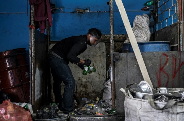 Un homme brise des bouteilles de verre pour les faire recycler, le 25 mai 2022 à Bogota 