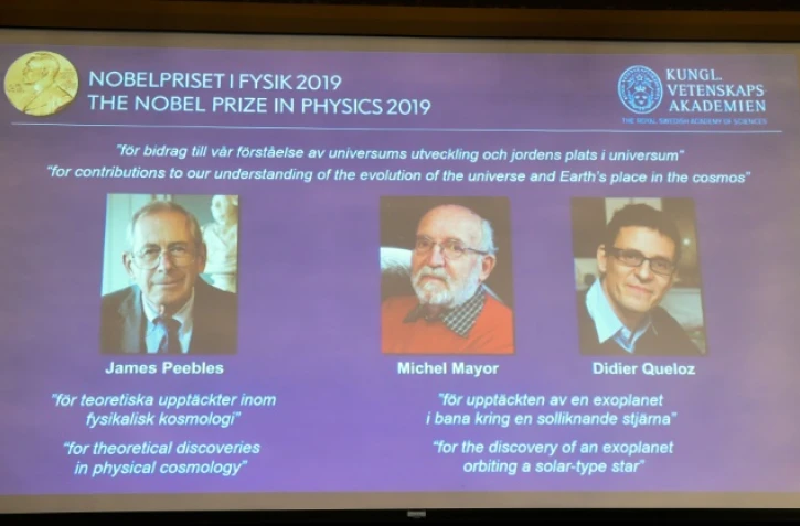 Un écran montre les lauréats du prix Nobel de physique, le Canado-américain James Peebles, et les Suisses Michel Mayor et Didier Queloz, à Stockholm le 8 octobre 2019
