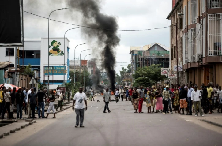 Des Kinois regardent des manifestants brûler des pneus au cours d'une marche anti-Kabila à Kinshasa, le 21 janvier 2018.