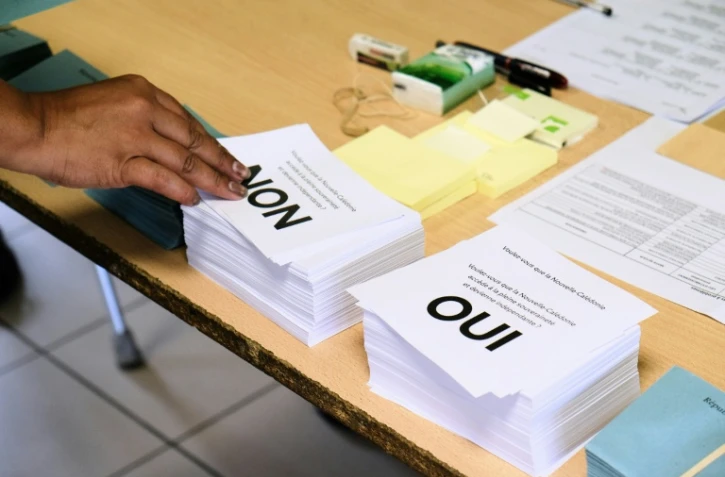 Une personne prend les bulletins avant de voter au référendum sur l'indépendance de la Nouvelle-Calédonie, le 4 octobre 2020 dans un bureau à Nouméa