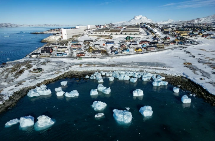 Des icebergs flottant dans les eaux avec des bâtiments en arrière-plan au large de Nuuk, au Groenland, le 11 mars 2025, le jour des élections législatives au Groenland, territoire autonome danois