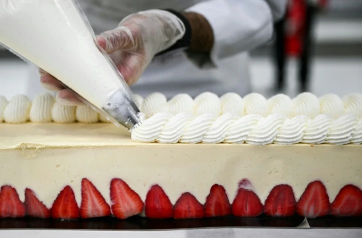 Un pâtissier travaille sur le plus grand fraisier du monde, d'une longueur de 121,88 m, à Argenteuil, le 23 avril 2025