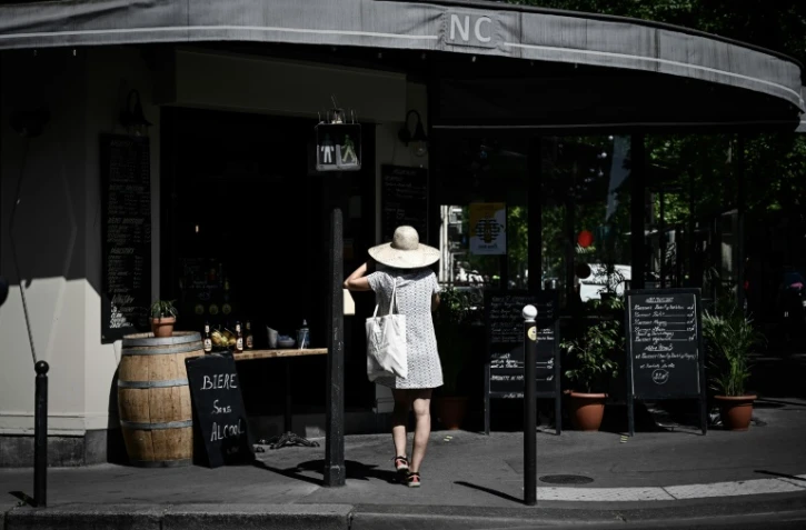 Une femme attend sa commande de plats à emporter devant un restaurant, le 27 mai 2020 à Paris