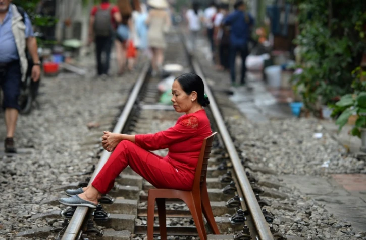 Une Vietnamienne assise sur une chaise posés sur les rails du chemin de fer dans le vieux quartier de Hanoï le 20 octobre 2018.