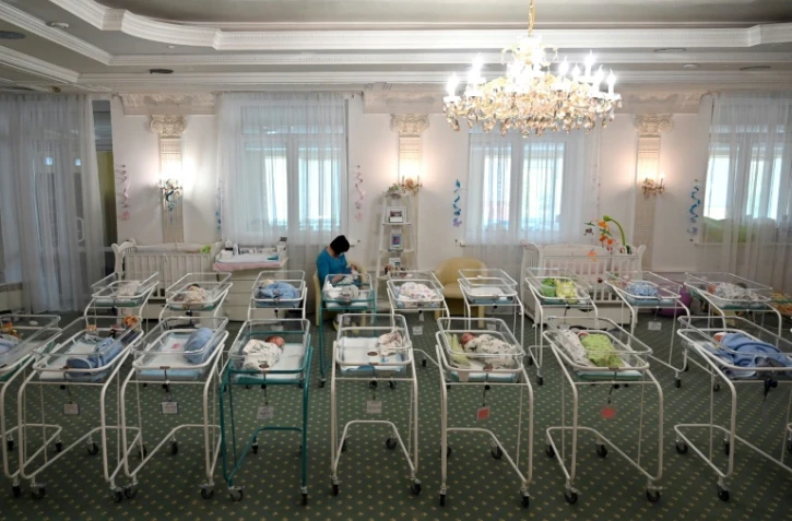 Une infirmière s'occupe de nouveaux-nés parmi la centaine de bébés nés de mères porteuses bloqués en Ukraine par la pandémie, à l'Hôtel Venice à Kiev le 15 mai 2020