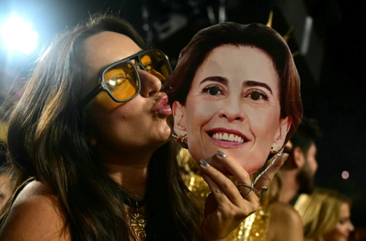 Une femme embrasse le masque de l'actrice brésilienne Fernanda Torres au sambodrome, durant le carnaval de Rio  le 3 mars 2025