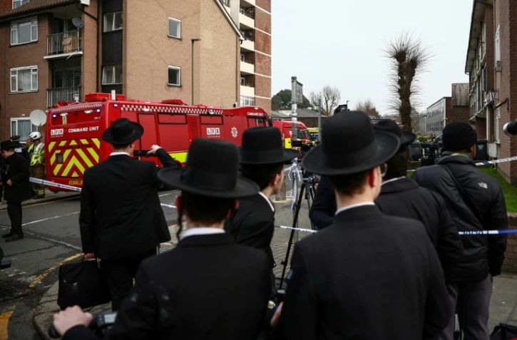 Des habitants sont rassemblés près d'un camion de pompiers après une attaque "antisémite" à Londres ayant visé quatre ambulances gérées par une association juive, le 23 mars 2026