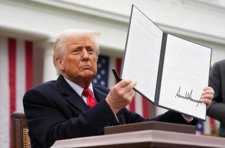 Le président américain Donald Trump brandit un décret sur les droits de douane, le 2 avril 2025 à la Maison Blanche, à Washington