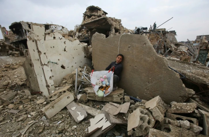 Un enfant avec quelques jouets récupérés dans les décombres de sa maison le 17 décembre 2016 à rubble of his house in Aleppo's Al-Arkoub dans la banlieue d'Alep