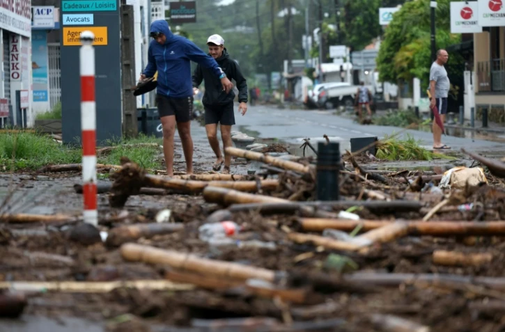 Des piétons au milieu des débris à Saint-Paul de la Réunion après le passage du cyclone Garance le 28 février 2025