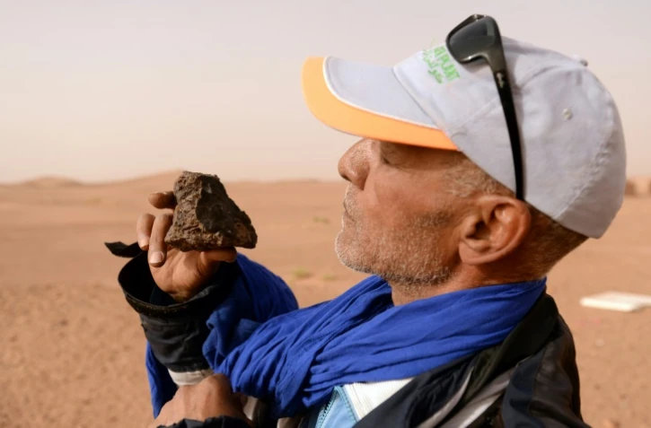 Un chasseur de météorite dans le sud du Maroc examine une roche près de l'oasis de M'hamid el Ghizlane, le 25 mars 2018