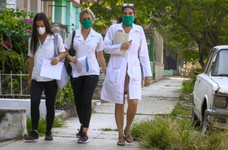 La docteure cubaine Liz Caballero (d) fait du porte-à-porte avec des étudiantes, en quête de nouveaux cas de coronavirus,le 31 mars 2020 à La Havane