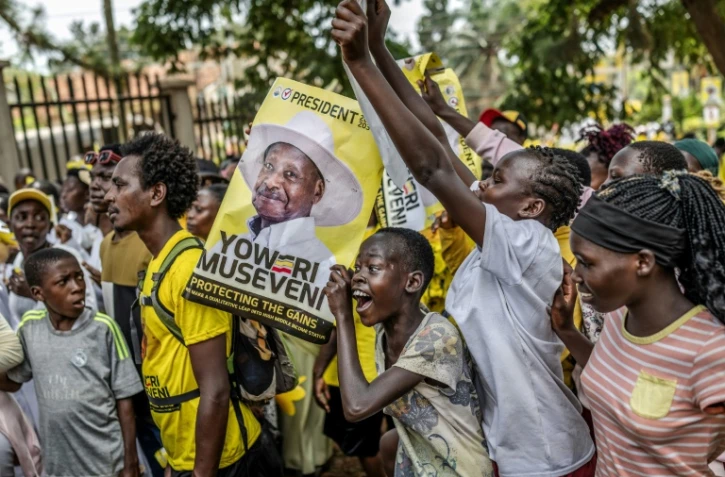 De jeunes partisans du président ougandais sortant Yoweri Museveni brandissent des affiches électorales et chantent des slogans à son dernier meeting de campagne, le 13 janvier 2026 à Kampala