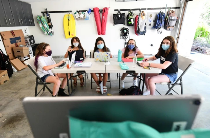 Des collégiennes suivent le cours en ligne de leur tuteur sur un iPad dans un garage, le 27 août 2020 à Calabasas, en Californie