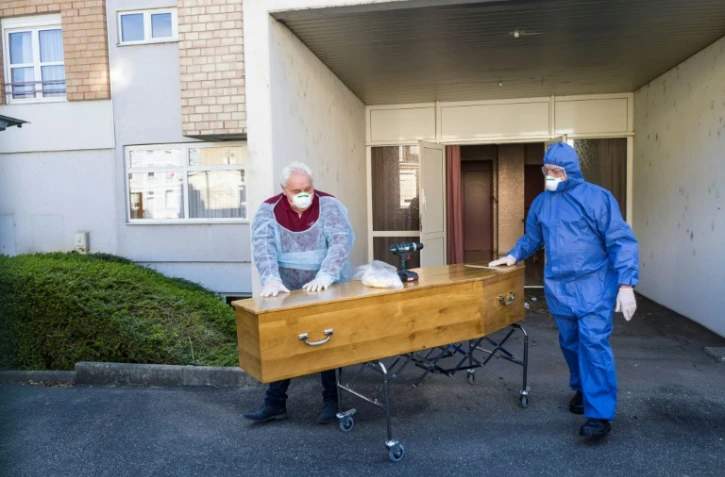 Des employés d'une société de pompes funèbres avec le cercueil d'une victime du coronavirus en EHPAD, à Mulhouse le 5 avril 2020
