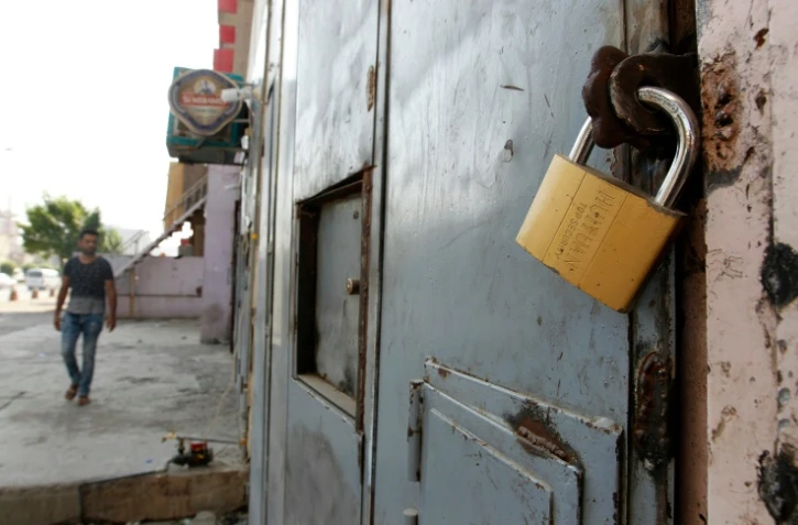 Un Irakien passe devant la porte fermée d'un magasin vendant de l'alcool à Bagdad le 23 octobre 2016 