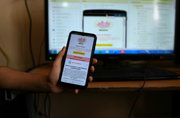 Rebeca Paredes, 16 ans, montre sur l'écran d'un téléphone l'application "Nezha" qu'elle a créée avec une amie du même âge pour informer sur "la sécurité" des établissements accueillant du public, à Caracas, le 19 mai 2021
Rebeca Paredes et Wanda Tremont, 16 ans toutes les deux, ont elles développé "Nezha", une "appli sur la sécurité" des établissements accueillant du public