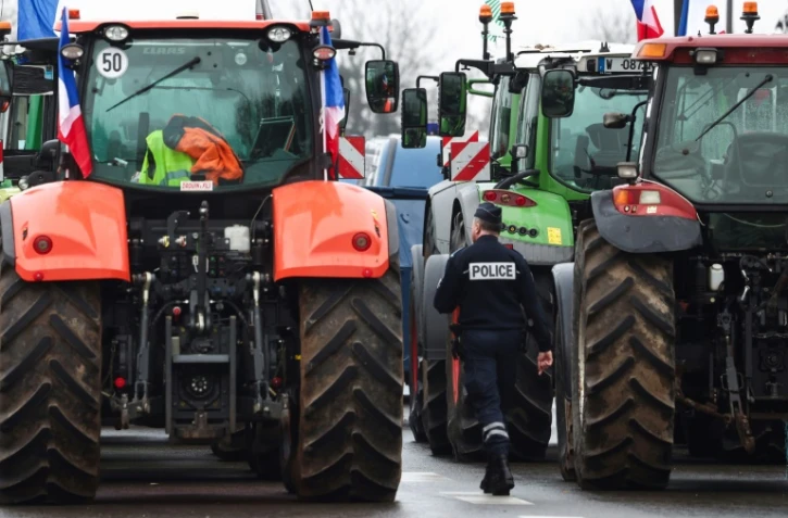 Un policier marche prÚs de tracteurs bloquant l'autoroute A6, le 1er février 2024 prÚs de Chilly-Mazarin en Essonne