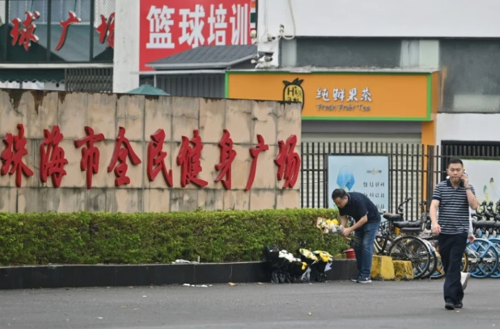 Des employés enlèvent des fleurs d'un lieu d'hommage improvisé devant le centre sportif de Zhuhai, deux jours après une attaque meurtrière à la voiture-bélier, le 13 novembre 2024 dans la province du Guangdong, dans le sud de la Chine