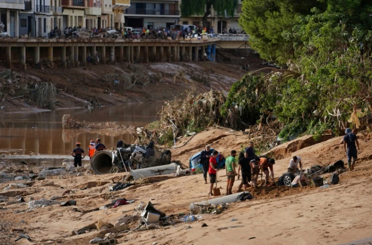 Des personnes tentent de dégager une voiture engloutie par la boue à la recherche de victimes, après les inondations qui ont frappé la région de Valence, le 1er novembre 2024 à Paiporta, en Espagne