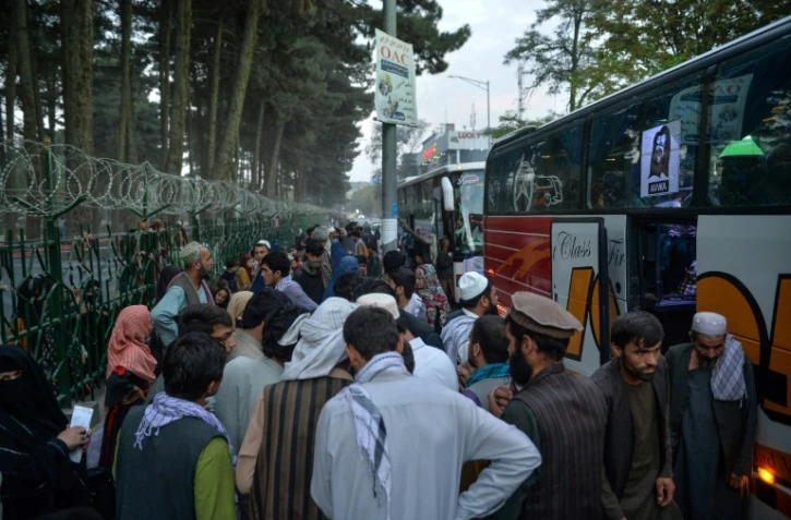 Des déplacés afghans installés dans un campement de fortune à Kaboul s'apprêtent  à monter dans un car pour retourner chez eux, le 29 septembre 2021