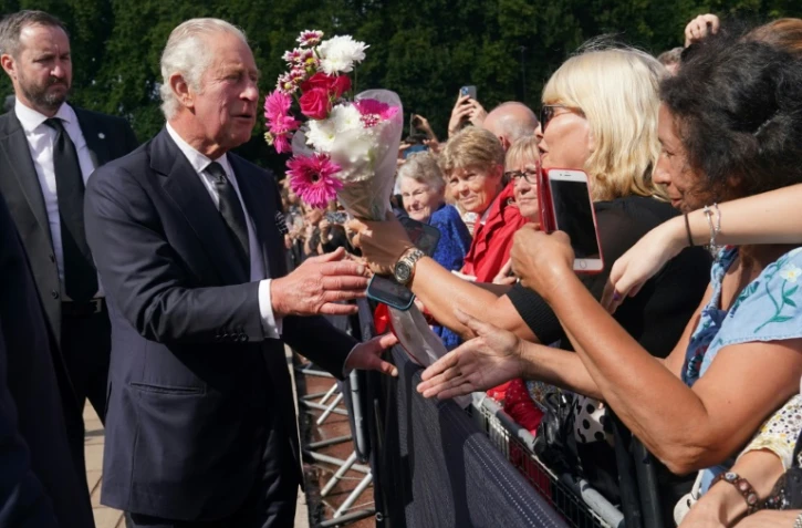 Le roi Charles III salue la foule à son arrivée au palais de Buckhingham, au lendemain du décès de la reine Elizabeth II, le 9 septembre 2022 à Londres