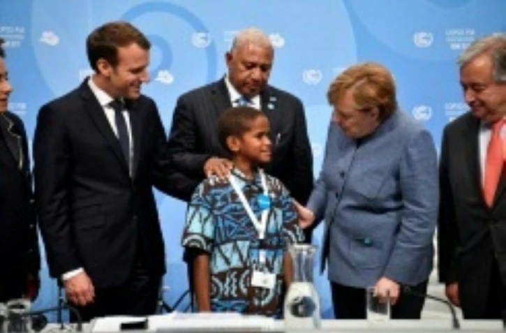 Timoci Naulusala un petit fidjien est félicité par le président Emmanuel Macron (g) et la chancelière Angela Merkel après son discours devant la COP 23 à Bonn