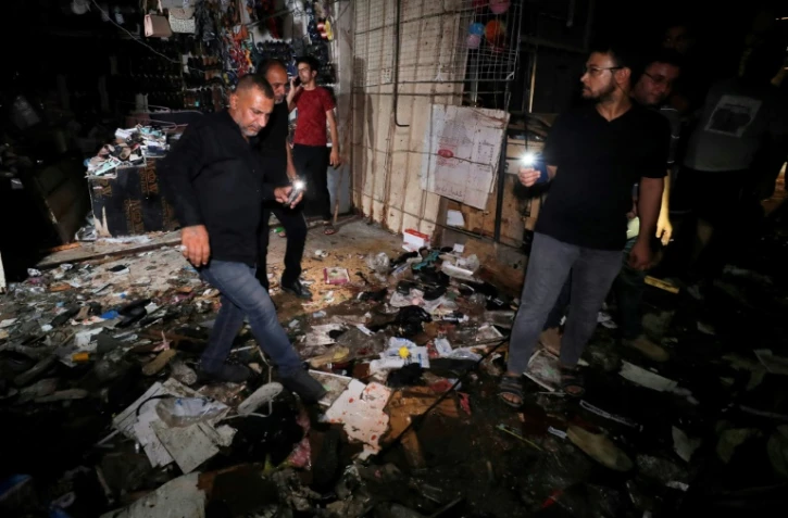 Des Irakiens inspectent les dégâts dans un marché de Bagdad après un attentat meurtrier, le 19 juillet 2021