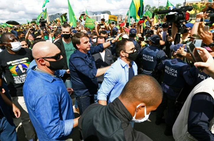 Le président du Brésil Jair Bolsonaro sans masque  accueille ses supporters, lors de son arrivée au palais présidentiel à Brasilia, le 24 mai 2020