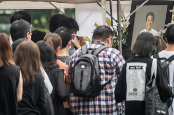 Des Japonais déposent des fleurs devant le temple de Tokyo où ont lieu mardi les funérailles de l'ex-Premier ministre Shinzo Abe le 12 juillet 2022