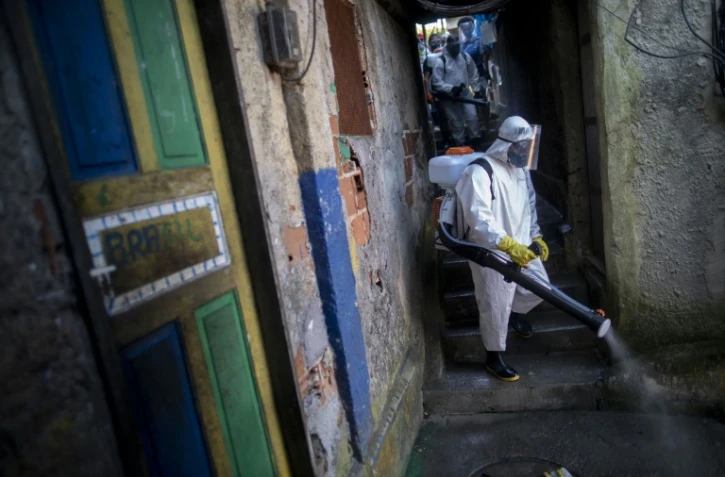 Un volontaire désinfecte une rue dans la favela Santa Marta de Rio de Janeiro le 20 avril 2020 dans le cadre de la lutte contre le coronavirus