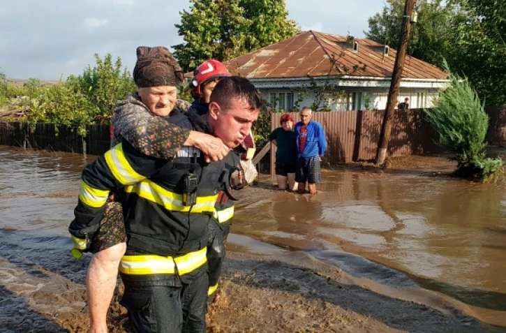 Un secouriste évacue une femme âgée, le 14 septembre 2024, dans le village inondé de Pechea, en Roumanie