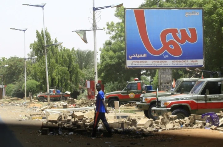 Un homme traverse une rue où sont postés des membres des Forces de soutien rapide (RSF), des paramilitaires accusés d'être à l'origine d'une vague de répression meurtrière, à Khartoum, le 10 juin 2019