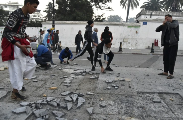 Des manifestants brisent des pavés à Alger tandis que la police fait usage de gaz lacrymogène, le 22 février 2019
