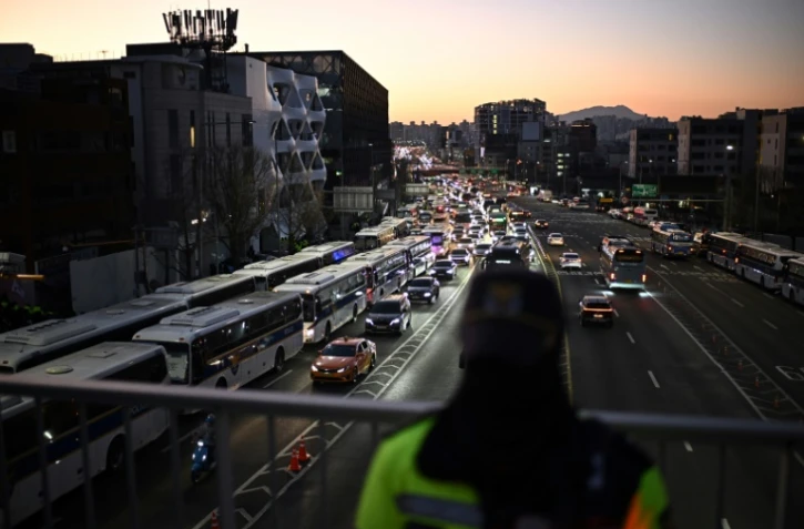 Des véhicules de la police sud-coréenne (gauche) sont rassemblés près de la résidence du président sud-coréen déchu Yoon Suk Yeol, le 3 janvier 2025 à Séoul