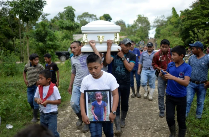 Un garçon porte une photo de Jakelin Caal, décédée aux Etats-Unis, pendant ses obsèques au Guatemala le 25 décembre 2018