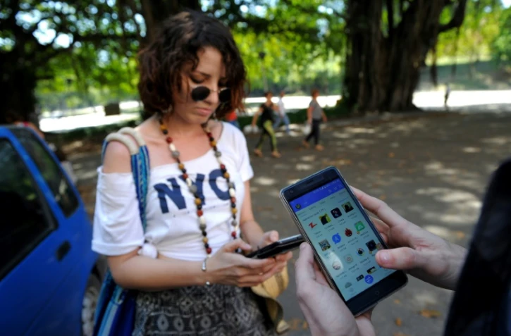 Des Cubains échangent des informations sur leurs tablettes et leurs smartphones via Zapya, une application permettant d'échanger des fichiers à courte distance, sans connexion filaire ni internet, le 14 février 2017 à La Havane