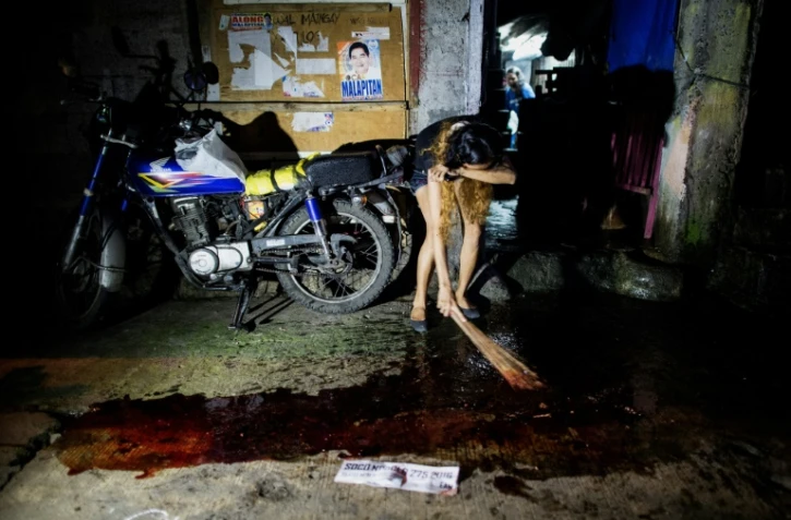 Après le meurtre d'un proche, une parente balaye en pleurant le sang devant sa porte, à Manille, le 22 septembre 2016
