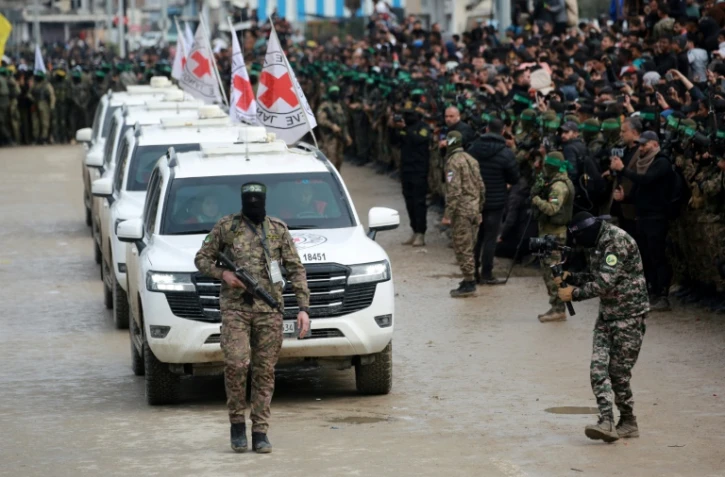 Des combattants du Hamas escortent un convoi de la Croix-Rouge arrivant à Nousseirat, dans la bande de Gaza, pour récupérer trois otages israliens le 22 février 2025