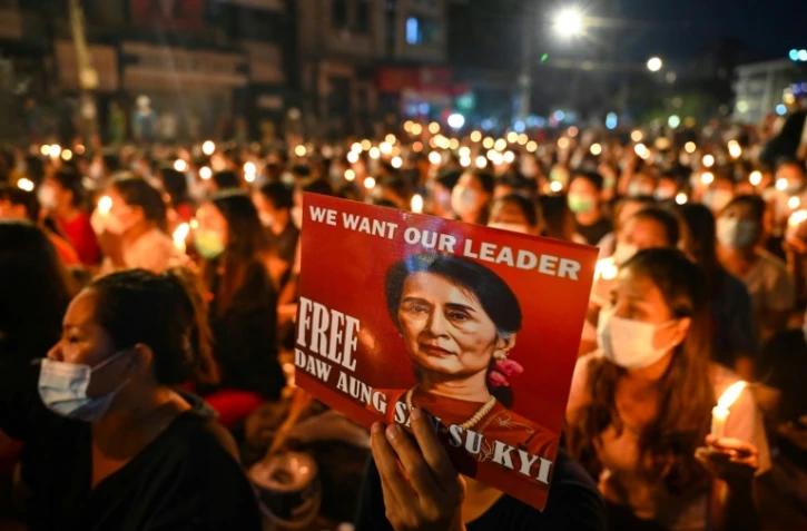 Un manifestant tient une affiche avec une image de l'ex-dirigeante détenue Aung San Suu Kyi lors d'une veillée aux chandelles à Rangoun, le 13 mars 2021