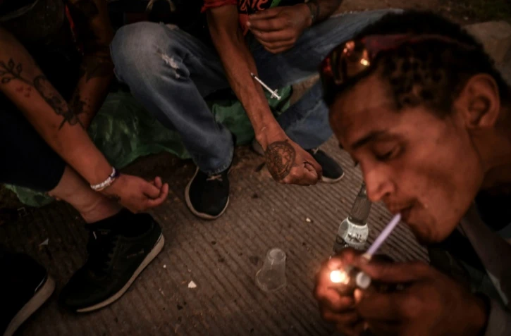 Un toxicomane fume du crack tandis que d'autres s'injectent de l'héroïne dans le centre-ville de Medellin, en Colombie, le 1er mars 2022