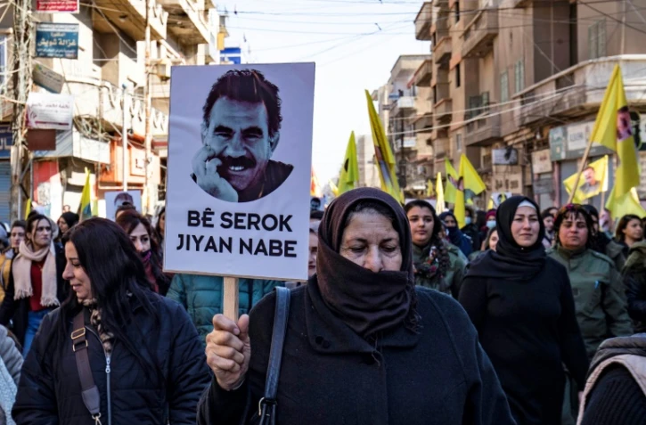 Des manifestants brandissent des drapeaux jaunes et un portrait représentant le visage d'Abdullah Öcalan, le chef du Parti des travailleurs du Kurdistan (PKK), actuellement emprisonné en Turquie, lors d'une manifestation à Qamishli, dans le nord-est de la Syrie, le 15 février 2023