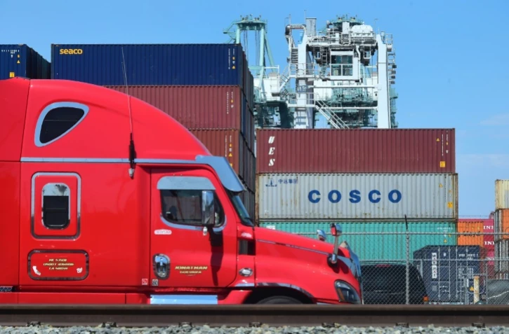 Un camion passe devant des conteneurs, dont l'un appartenant au groupe chinois Cosco, le 6 juillet 2018 dans le port de Long Beach, en Californie
