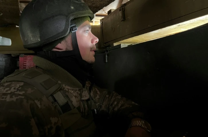 Un soldat ukrainien surveille depuis un abri les lignes de l'armée russe, près de Kharkiv, le 17 avril 2022