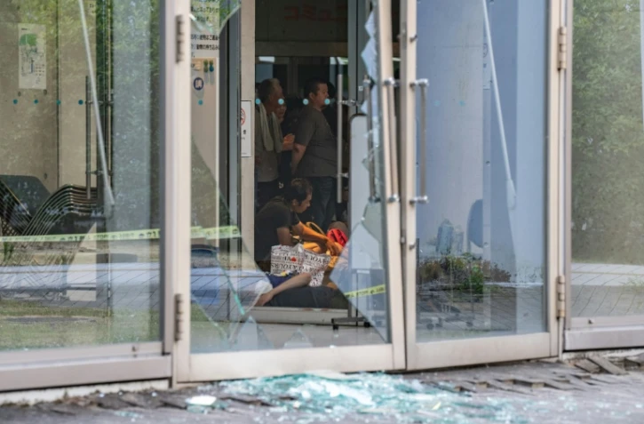Des éclats de verre jonchent le sol tandis que des évacués se reposent dans un centre d'hébergement aménagé à l'hôtel de ville d'Uki, dans la préfecture de Kumamoto, le 29 juillet 2026, au lendemain du séisme qui a frappé le sud-ouest du Japon