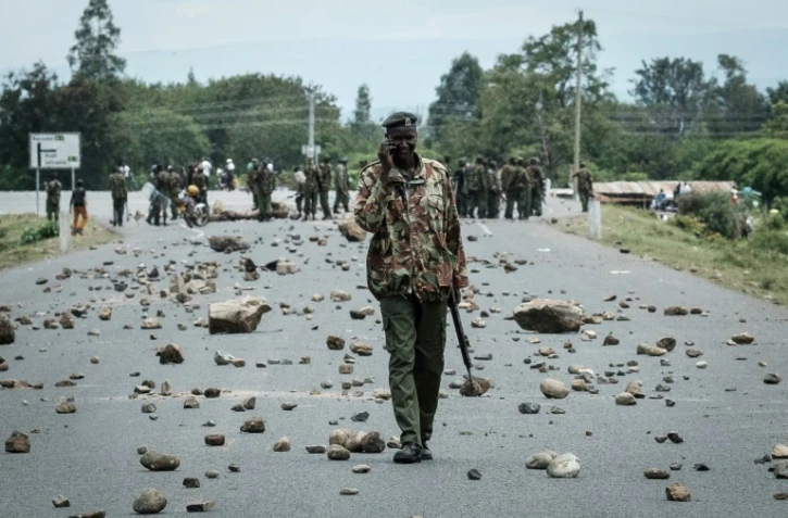Un policier kényan marche sur une route couverte de pierres érigées en barricades par des partisans de l'opposition à Ahero, à environ 25 km à l'est de Kisumu, le 26 octobre 2017