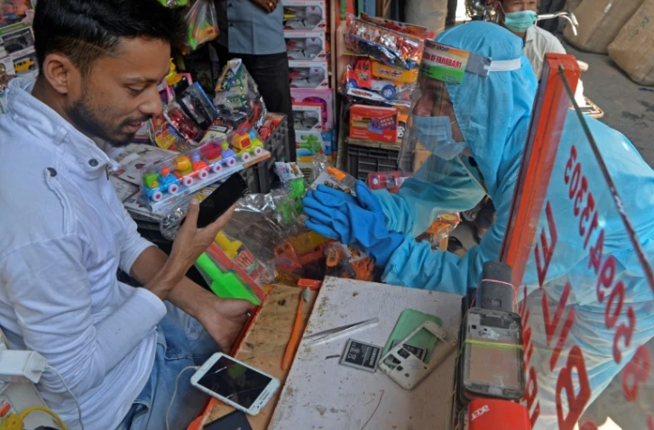 Un bénévole demande à un vendeur de porter un masque dans son échoppe pour lutter la diffusion du Covid-19, le 23 avril 2021 à Siliguri, en Inde