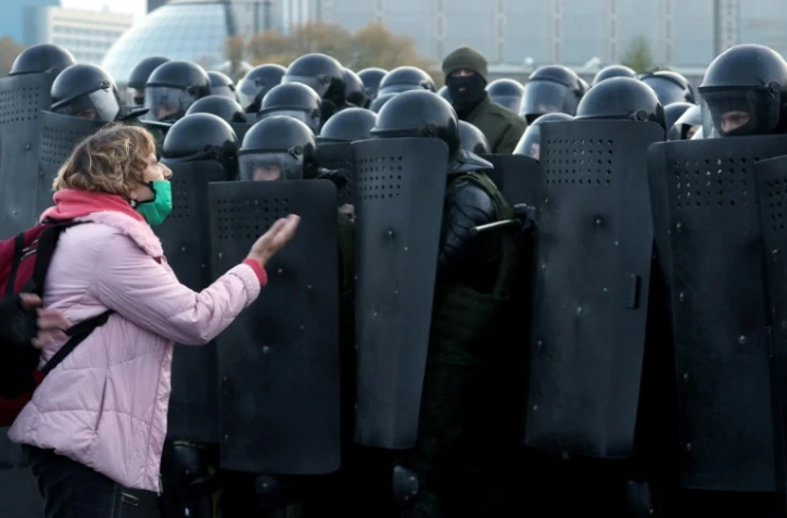 Une femme parle avec des policiers anti-émeute pendant une manifestation à Minsk, le 25 octobre 2020. 