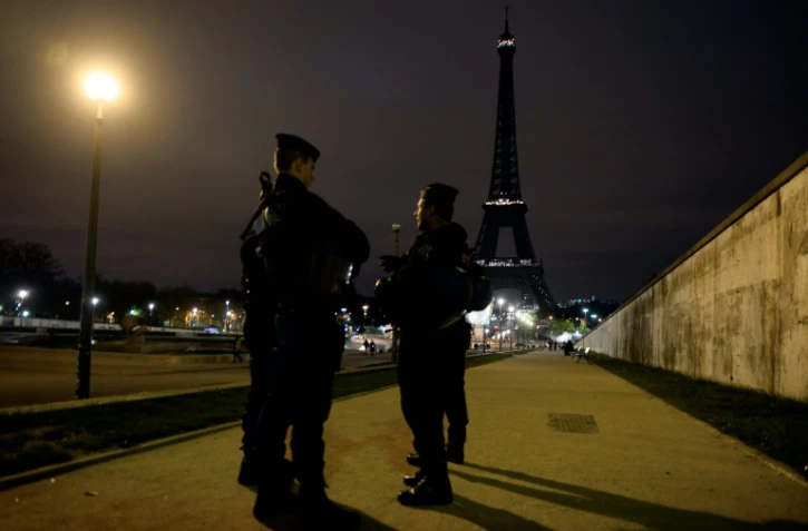Des policiers devant la Tour Effeil éteinte en hommage aux victimes des attentats de Paris, le 14 novembre 2015